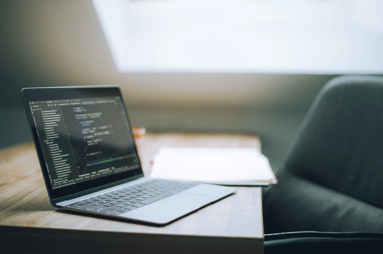 Laptop displaying code and web design layout in clean studio