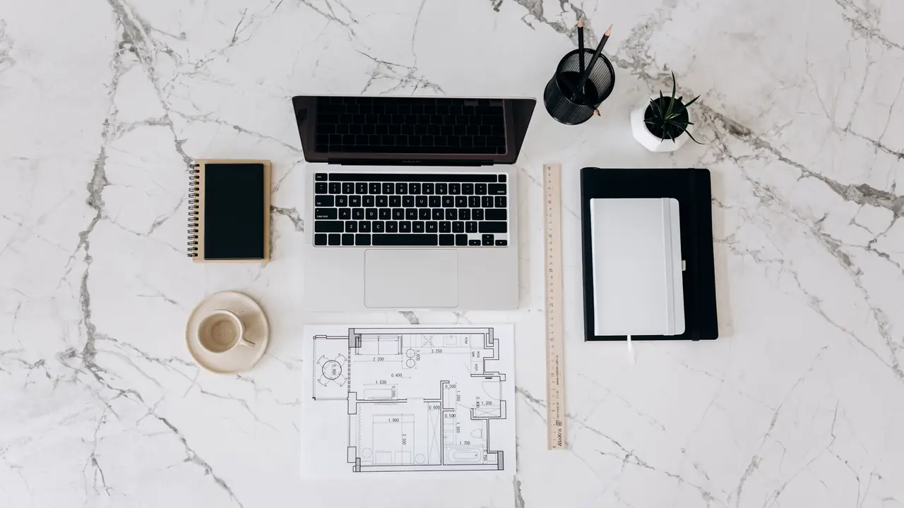 Organised designer workspace with architectural blueprint, laptop and measurement instruments
